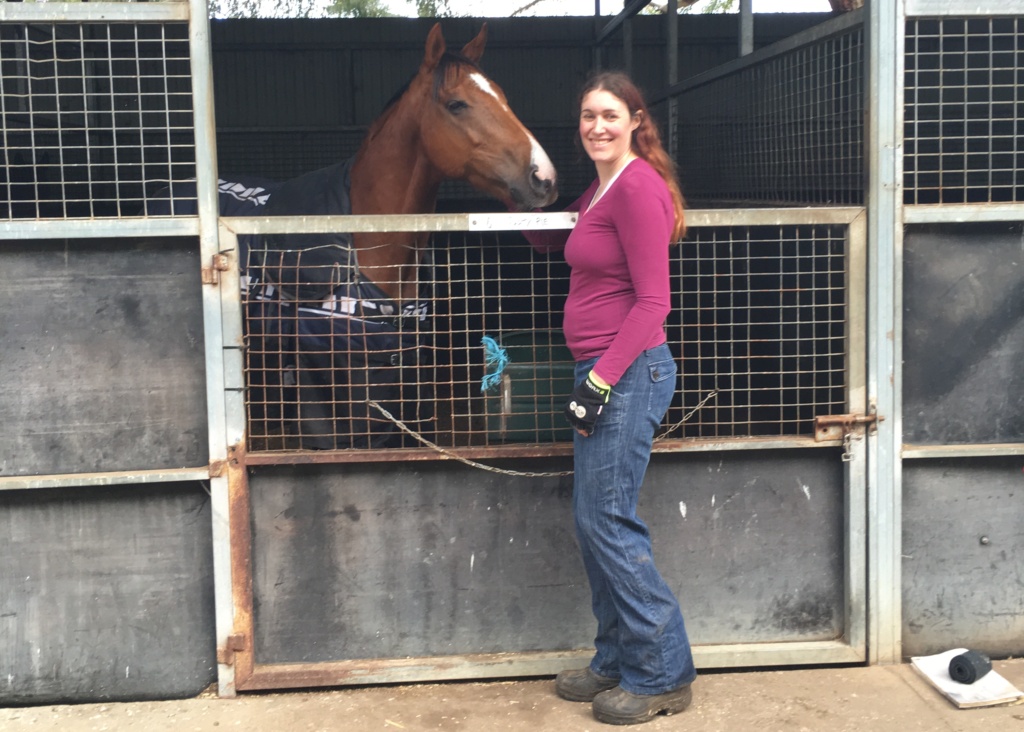 Passionate job seeker Kylie standing with one of the horses she now works with as a stable hand